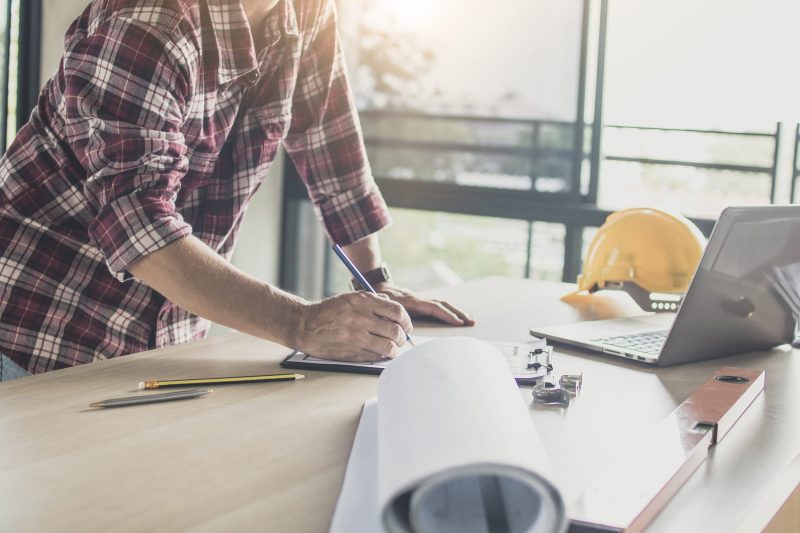 Man writing on notepad while looking at laptop